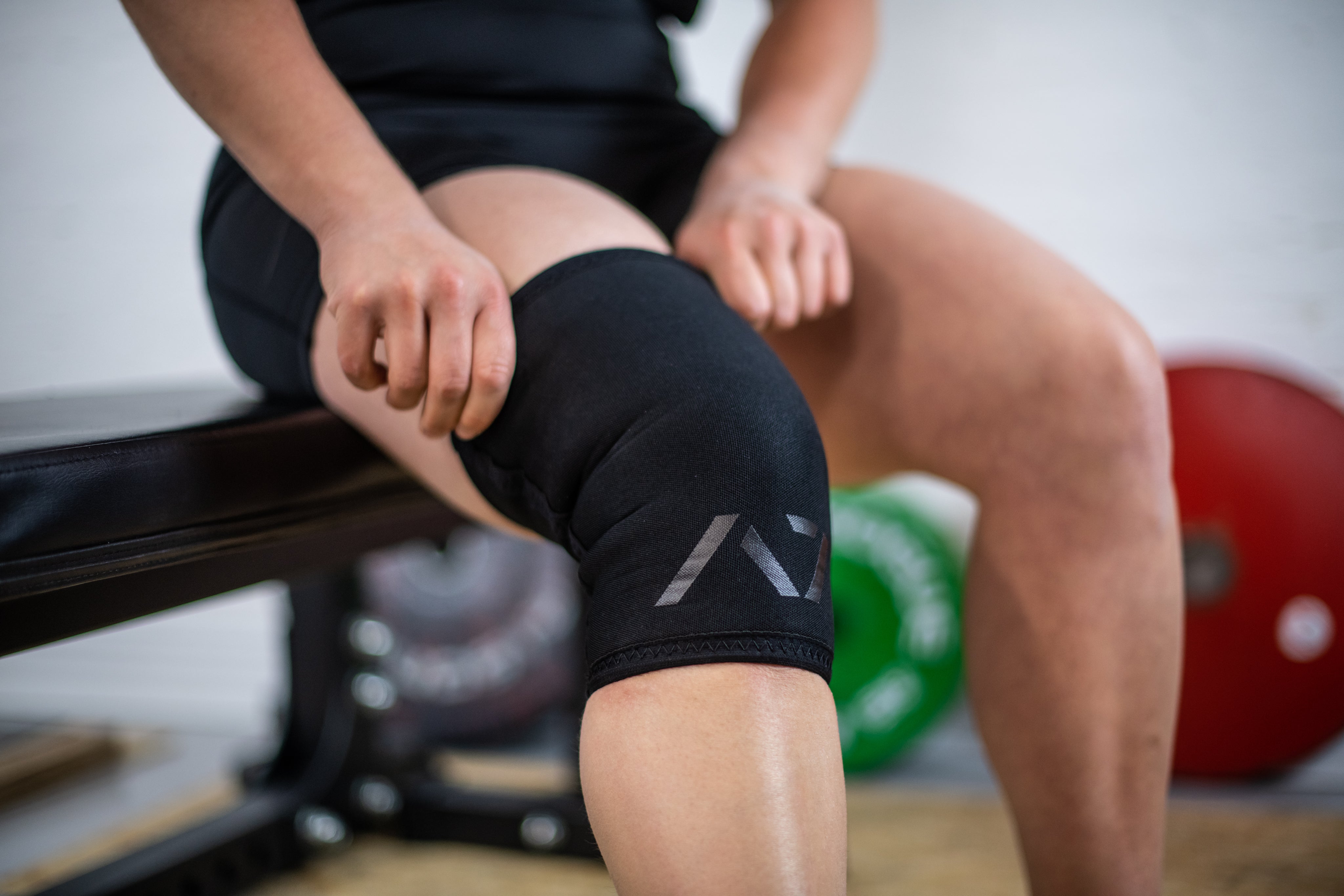 Athlete wearing A7 Stealth Stiff CONE Knee Sleeves during squat, demonstrating fit and support.
