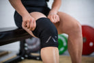 Athlete wearing A7 Stealth Stiff CONE Knee Sleeves during squat, demonstrating fit and support.